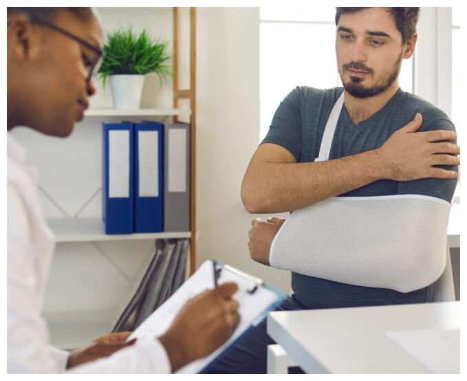 man with an injured arm being examined by a doctor