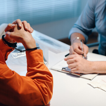criminal in handcuffs meeting with their attorney